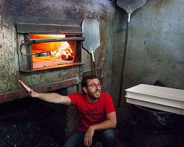 tour guide explaining coal fired pizza oven Patsy's in East Harlem