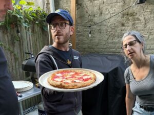 people holding up a pizza outside