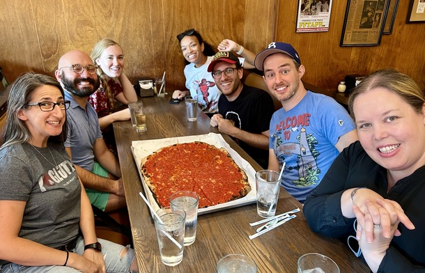 a group of happy people enjoying a regular pizza at sally's in new haven, ct