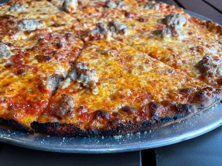 thin crust pizza with large chunks of sausage